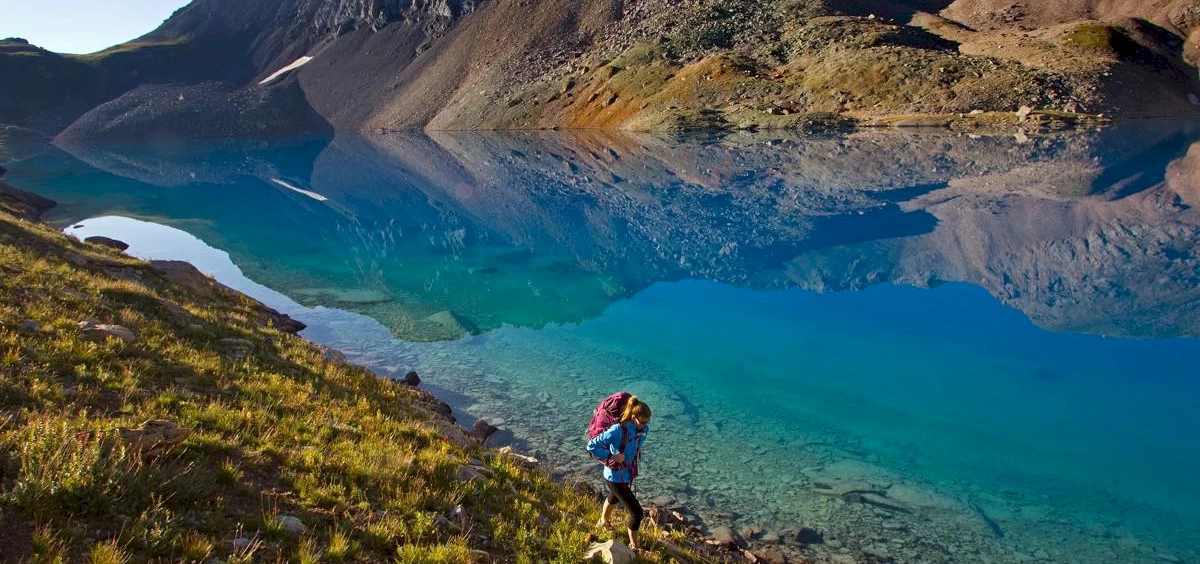 image of a hiker next to a lake | Telluride