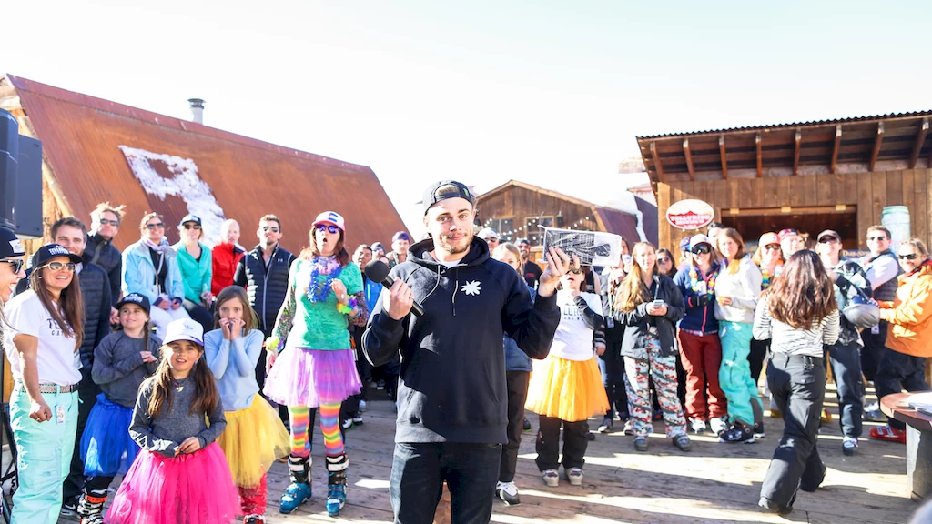 guy with a microphone standing in a crowd dressed in rainbow colors for Telluride Gay Ski Week